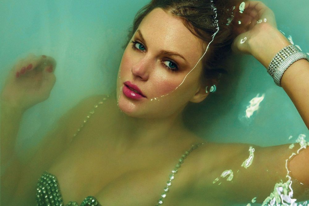 Taylor usa um figurino extravagante e está deitada em uma banheira com água que quase cobre o seu rosto maquiado