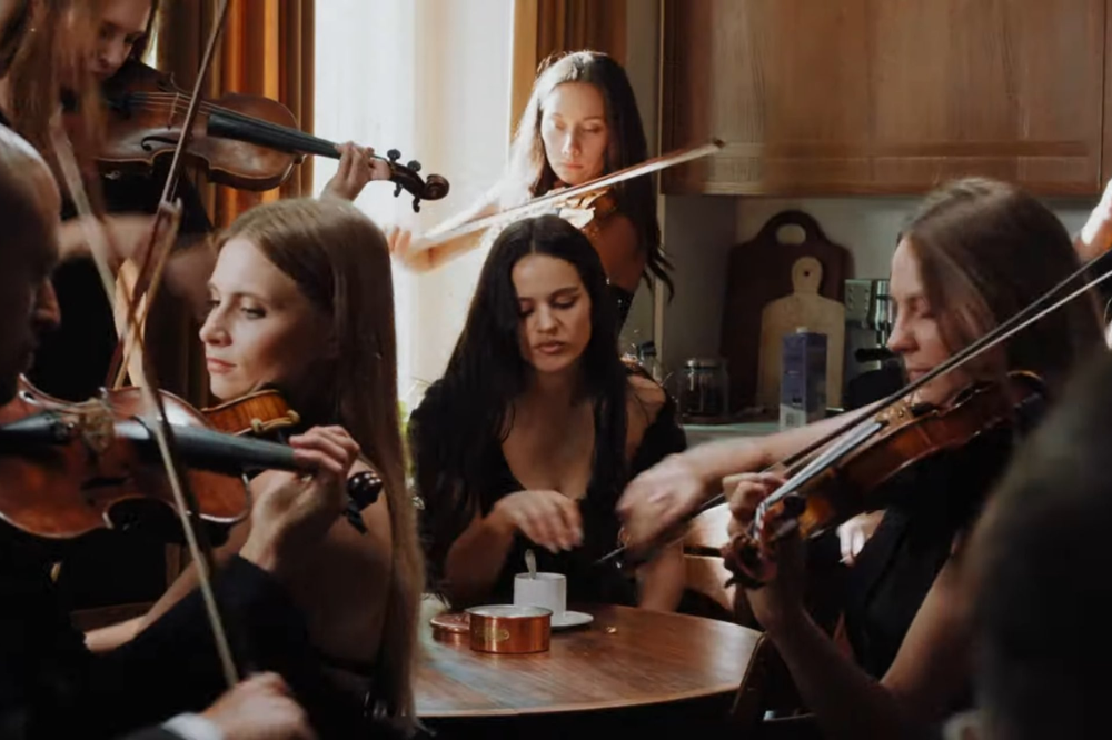 Rosalía tomando café rodeada por orquestra